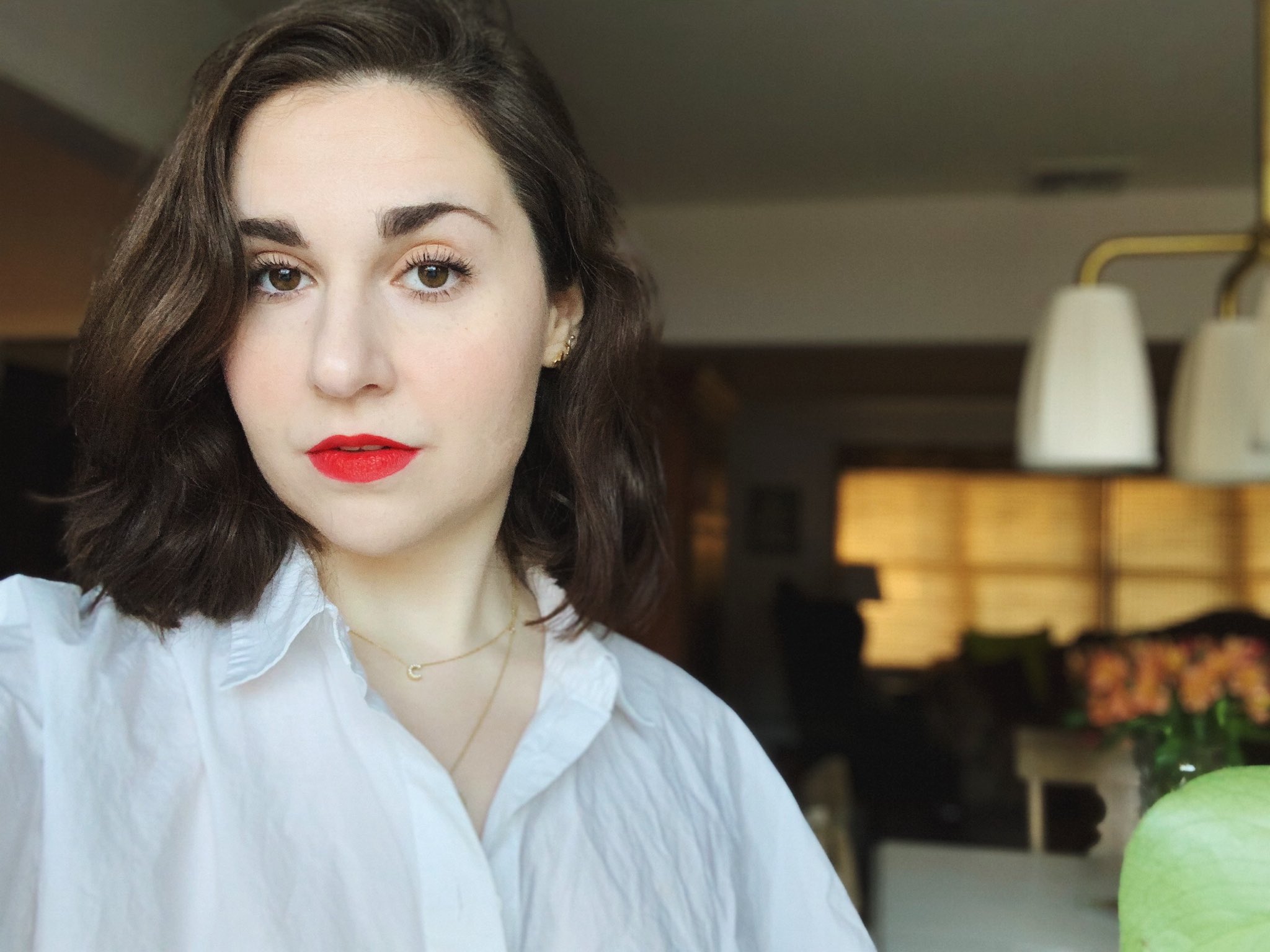 Woman with dark wavy hair and red lipstick looking at the camera 