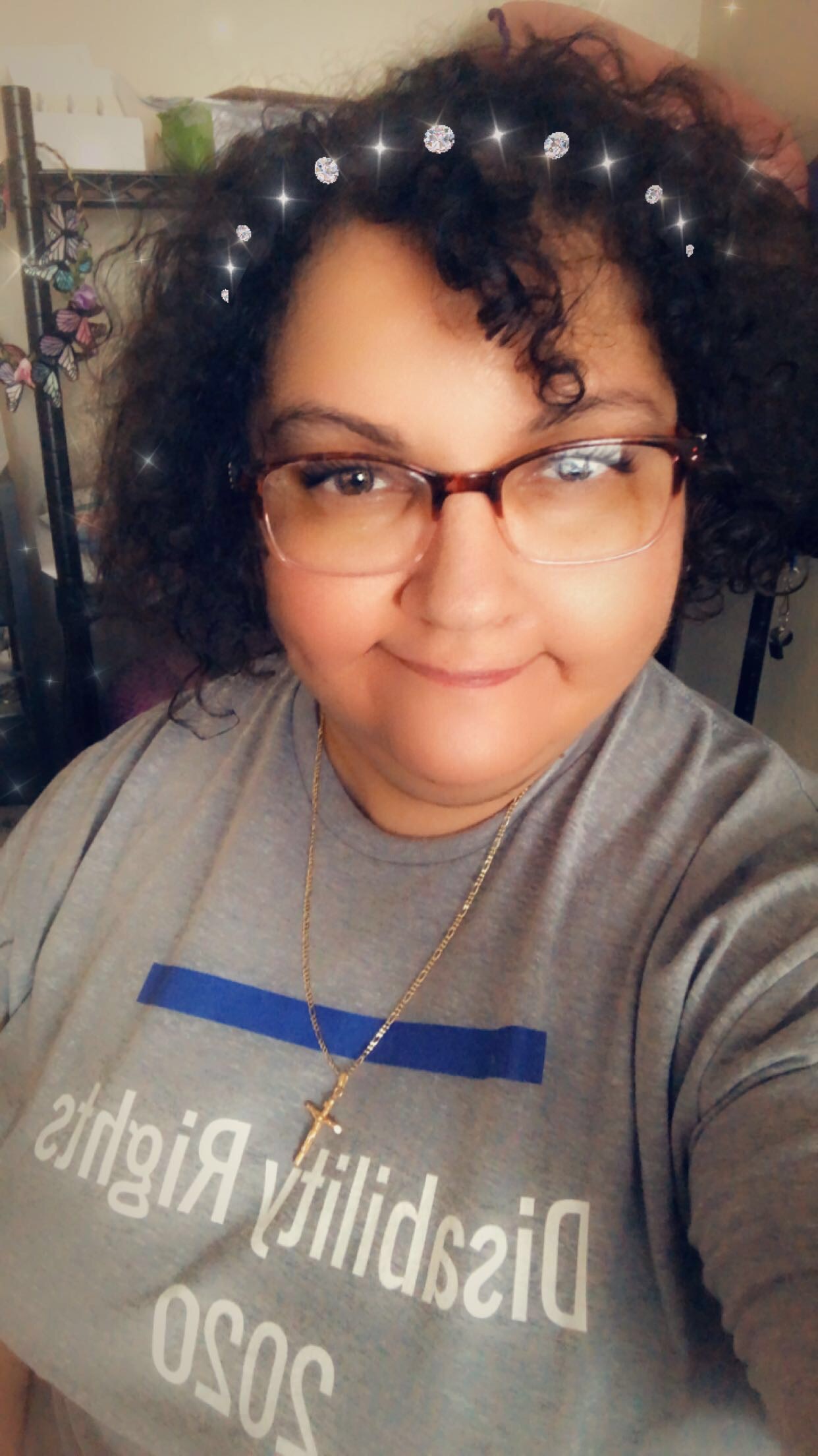 White woman with curly dark hair and glasses smiling at camera