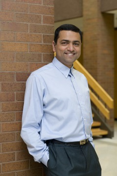 Picture of Raja Kushalnagar smiling, leaning against a wall.