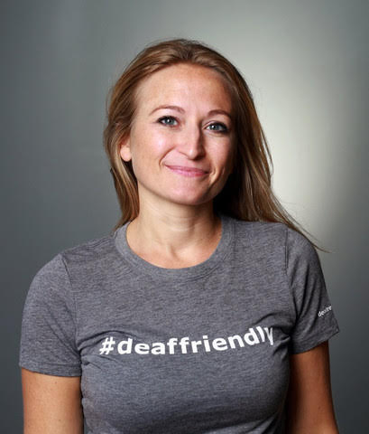 Picture of Melissa Greenlee smiling, wearing a gray shirt that says #deaffriendly