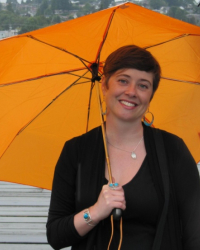 erson with short dark hair smiling, holding an orange umbrella
