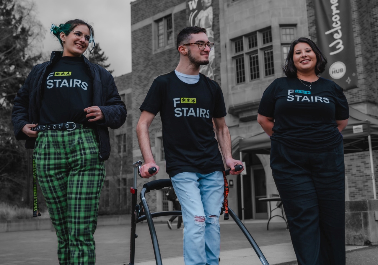 Three students walking in front of the HUB, laughing, wearing F*** Stairs T-Shirts